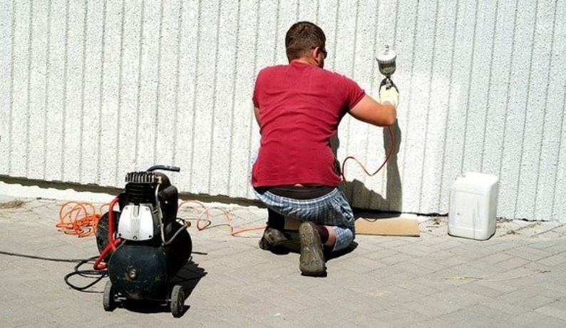 Mężczyzna malujący agregatem malarskim elektrycznym