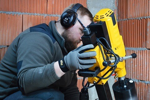 Mężczyzna obsługujący wiertnice na statywie