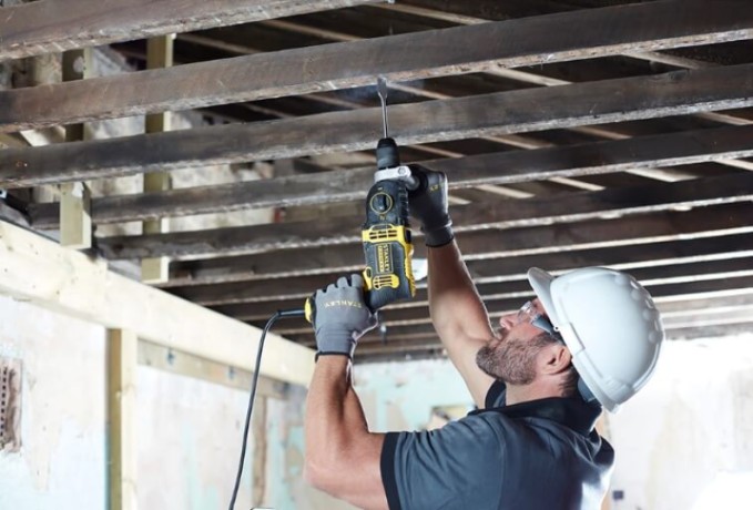 Pracownik budowlany pracujący z wiertarką STANLEY