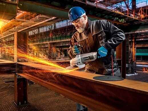 Mężczyzna w stroju ochronnym szlifujący metalową powierzchnię