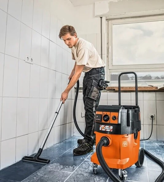 Instalator używający odkurzacza przemysłowego po skończonych pracach